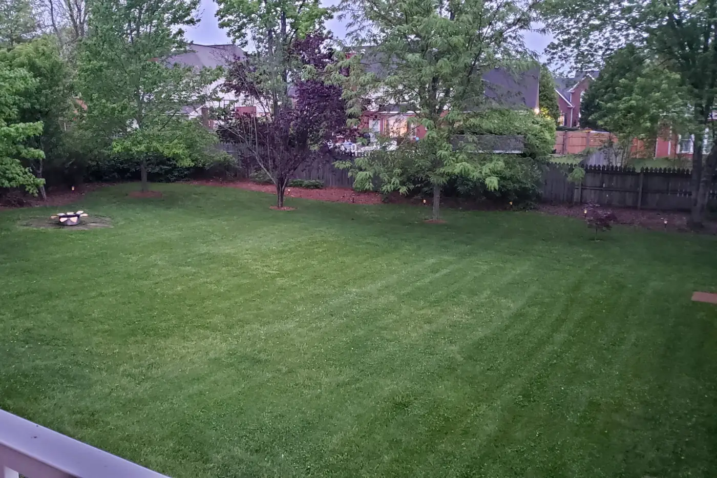 A mown lawn with clean edges and mulched beds along the fence line
